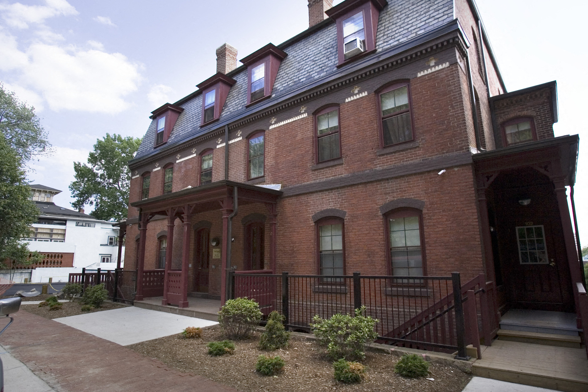 a red brick house with a front porch and a sidewalk